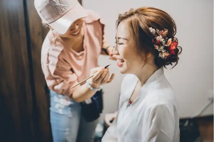 a woman smiling while applying makeup